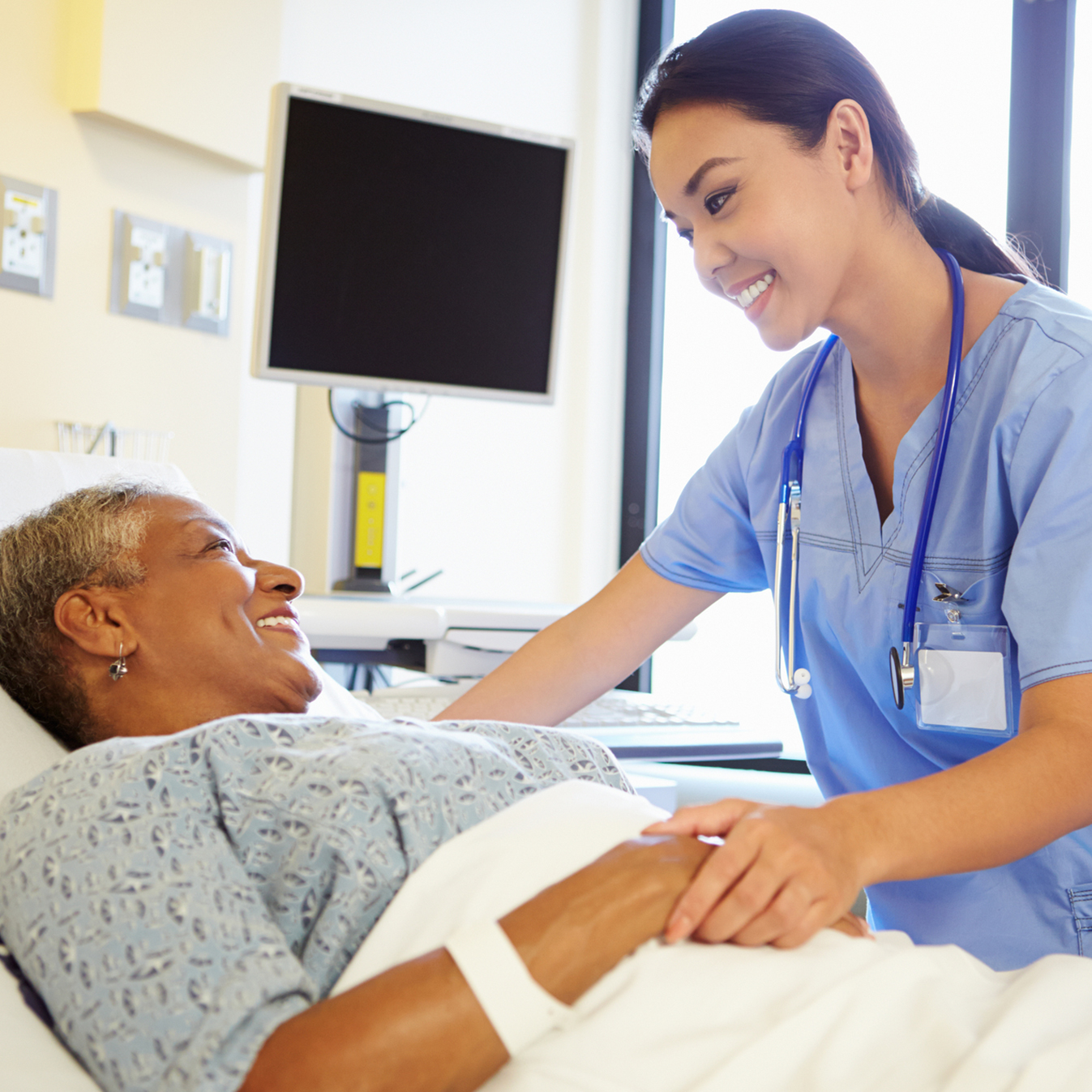 Nurse Talking To Senior Woman In Hospital Room