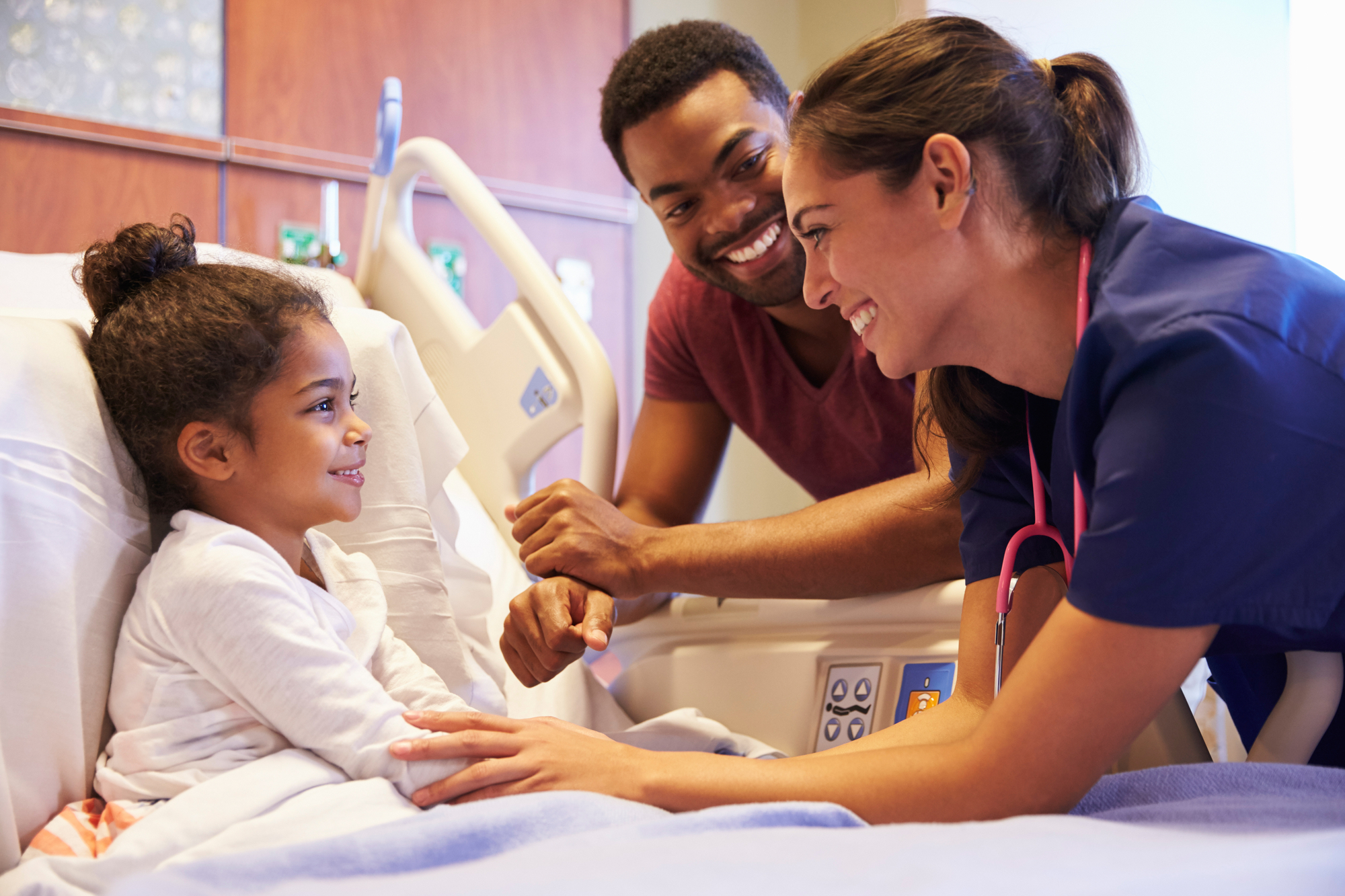 Nurse Visiting Father And Child In Hospital Bed